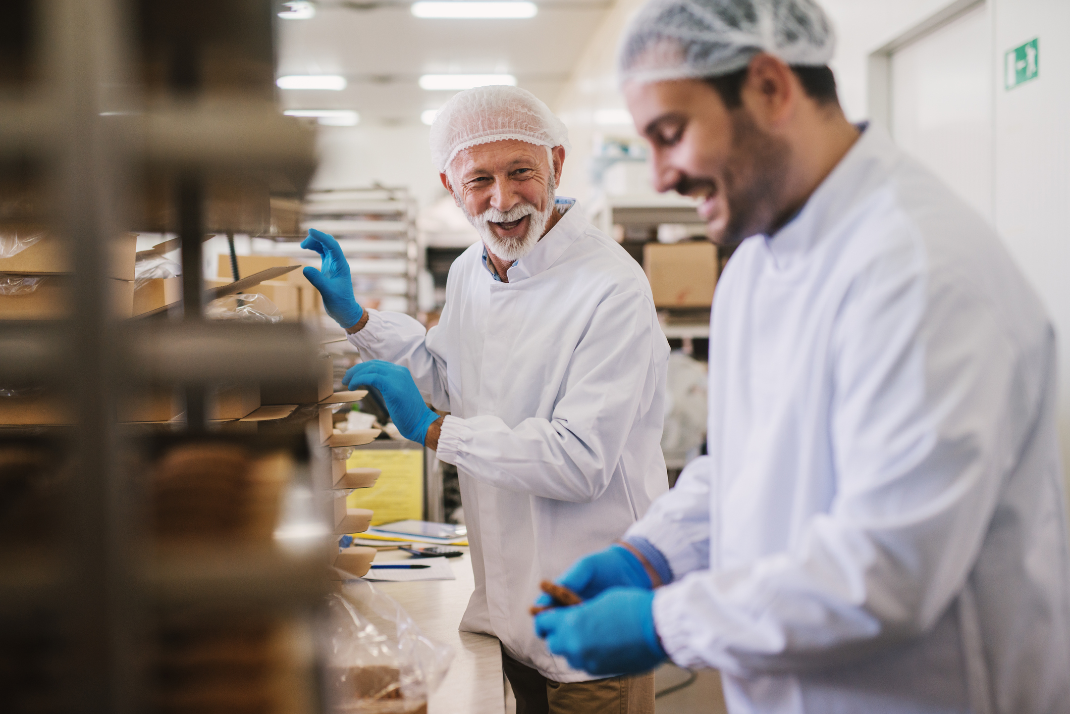 Picture of two male food factory employees in sterile clothes packing